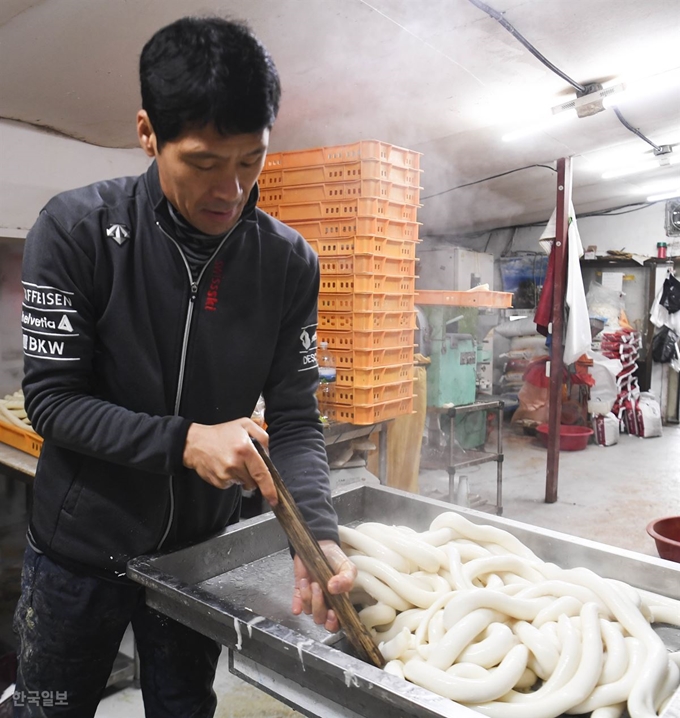 [저작권 한국일보] 50년 넘게 전통의 방식대로 떡을 만들어온 경기 고양시의 식사떡방앗간. 13일 오전 장기덕 대표가 하얀 가래떡을 뽑아 찬물에 식히고 있다. 박형기 인턴기자