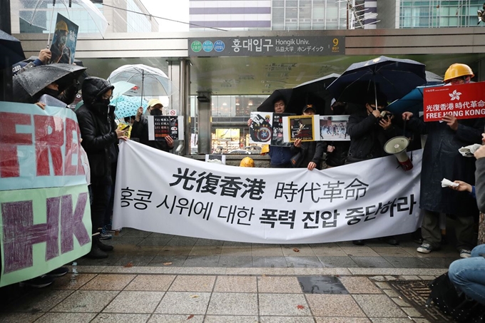 17일 오후 서울 마포구 홍대입구 지하철역 9번출구 앞에서 홍콩민주화지지모임 회원들이 현수막과 손피켓을 들고 홍콩 시위에 대한 지지를 호소하고 있다. 뉴시스