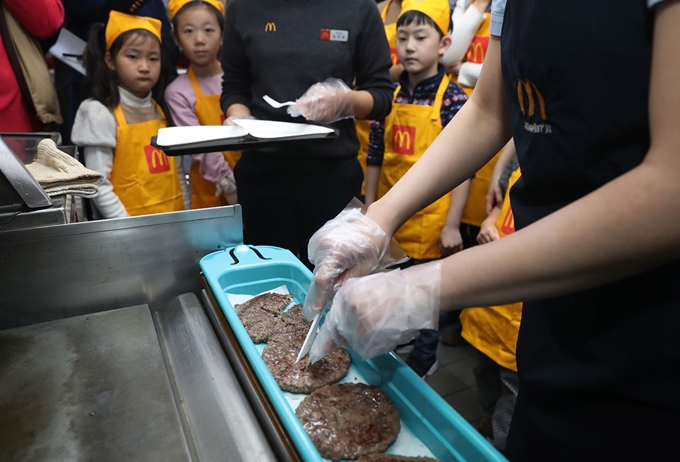 19일 서울 맥도날드 상암DMC점에서 열린 '맥도날드 주방 공개의 날' 행사에서 참가자들이 패티 시식을 기다리고 있다. 최근 시민단체로부터 위생 문제를 지적 받은 맥도날드는 이날 참여 희망 고객에게 전국 310여개 매장 주방을 공개했다. 연합뉴스