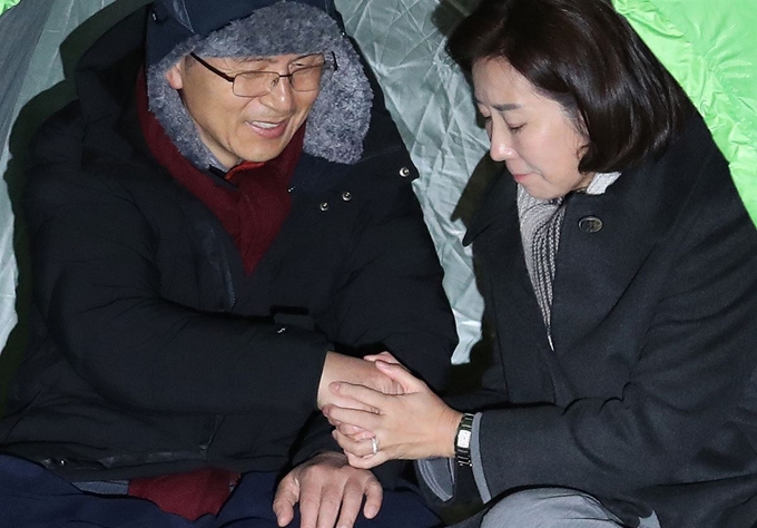 자유한국당 나경원 원내대표가 23일 오전 미국에서 돌아온 뒤 청와대 앞 분수대 광장을 찾아 단식투쟁 나흘째를 맞이한 황교안 대표의 손을 꼭 잡아주고 있다. 연합뉴스