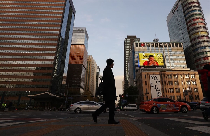 지난 18일 정부가 내년부터 시행키로 한 50~299인 규모의 기업에 대한 주52시간 근로제 적용을 한시적으로 유예키로 했다. 이날 오후 직장인으로 보이는 시민이 해질녘 광화문네거리를 지나고 있다. 연합뉴스