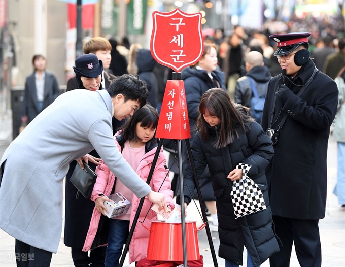 구세군이 29일부터 자선냄비 거리모금을 시작한 가운데 서울 명동을 지나던 시민들이 헌금을 하고 있다. 거리모금은 내달 말일까지 진행된다. 홍인기 기자