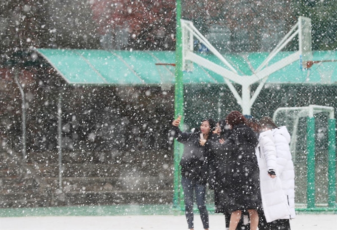 3일 오전 경기도 군포시 산본고등학교에서 학생들이 내리는 눈을 맞으며 사진을 찍고 있다. 연합뉴스