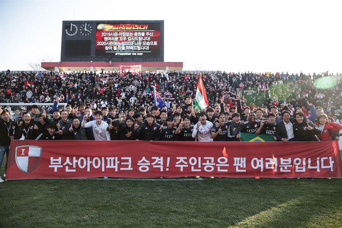 부산아이파크 선수와 팬들이 8일 창원축구센터에서 열린 하나원큐 K리그 승강 플레이오프에서 경남에 승리를 거둔 뒤 K리그1 승격을 자축하는 기념사진을 촬영하고 있다. 한국프로축구연맹 제공