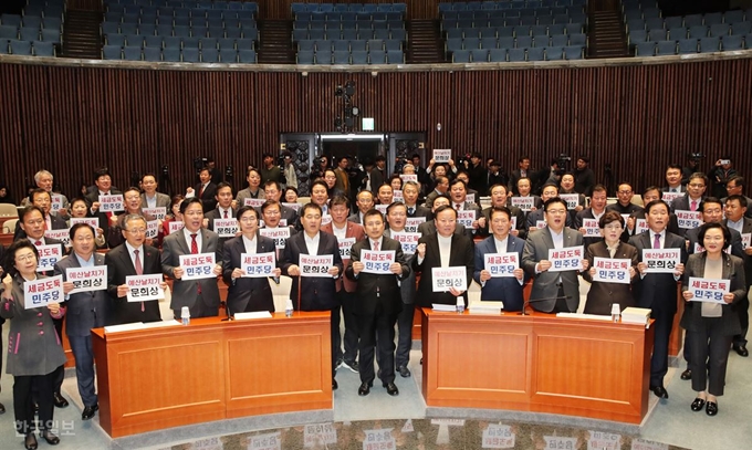 자유한국당 황교안(앞줄 가운데) 대표와 의원들이 11일 국회 예결위 회의장에서 열린 의원총회에 예산안 날치기 통과 관련 손피켓을 들고 구호를 외치고 있다. 홍인기 기자