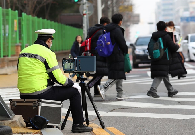 대전 둔산경찰서 관계자가 11일 오후 서구 둔산동 한 초등학교 앞 어린이보호구역(스쿨존)에서 과속 차량을 단속하고 있다. 국회는 전날 스쿨존에 과속단속 카메라 설치를 의무화하고, 스쿨존 내 사망사고 가해자를 가중처벌하는 것을 골자로 하는 ‘민식이법’을 상정·처리했다. 연합뉴스