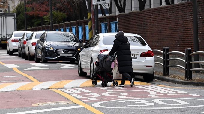 13일 오후 서울 강남구 개포동의 어린이보호구역에서 한 시민이 불법 주정차된 차량을 피해 유모차를 밀고 가고 있다.