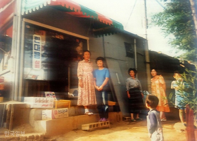 1980년대 구자태씨가 경기 광명에서 운영하던 잡화점. 어머니와 누나가 문 앞에 서 있고 오른쪽은 이웃들이다. 대한주택공사가 이 가게 철거 대가로 준 상가 분양권은 31년째 무용지물이다. 구자태씨 제공