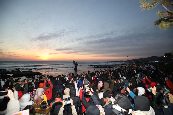 전국 각지에서 경북 포항시 남구 호미곶면을 찾은 관광객들이 지난 1월 1일 호미곶을 나타내는 조형물 '상생의 손' 뒤로 새해 첫 해가 떠오르자 사진촬영을 하고 있다. 포항시 제공