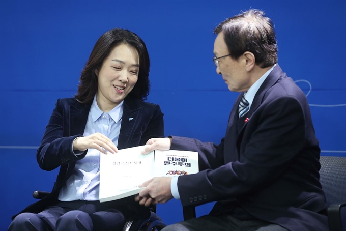 더불어민주당 이해찬 대표가 26일 서울 여의도 당사에서 '총선 영입인재 1호'인 최혜영 장애인식개선교육센터 이사장에게 당헌, 당규 책자를 전달하고 있다. 최 이사장은 신라대 무용학과를 다니며 발레리나의 길을 걷던 2003년 스물넷의 나이에 교통사고로 사지마비 척수장애 판정을 받았다. 연합뉴스