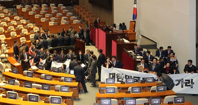 자유한국당 의원들이 27일 오후 국회 본회의가 열리기에 앞서 '연동형비례대표제' 선거법 반대 현수막을 펼치고 의장석 주변을 둘러싸고 있다. 연합뉴스