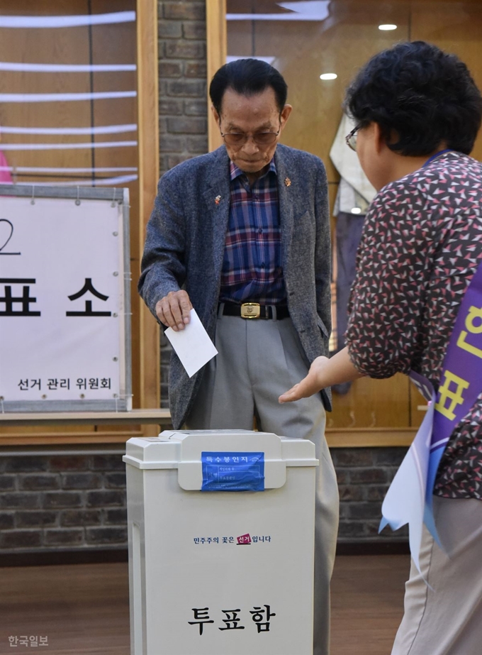 차상덕 호찌민노인회 고문이 선관위원의 안내를 받아 기표한 투표용지를 함에 넣고 있다.