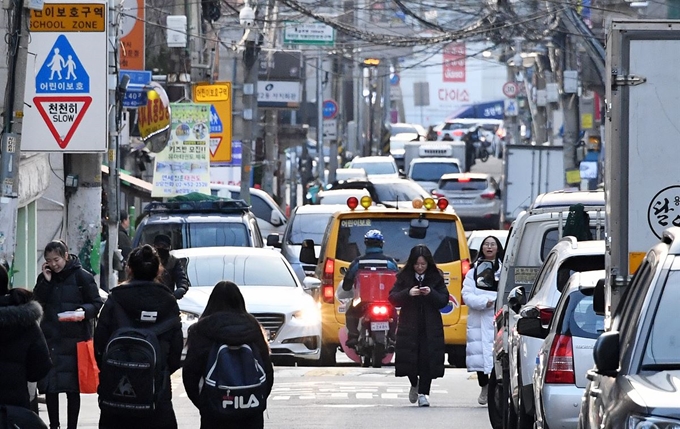 지난 13일 오후 서울 광진구 광진초등학교 인근에 설정 어린이보호구역에 주차된 차량과 통행하는 차량들을 피해 학생들이 이동하고 있다. 김주영 기자