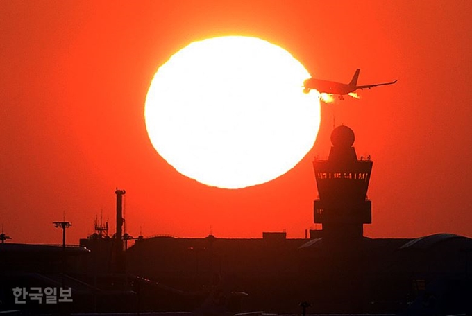 인천공항 제2여객터미널 관제탑 위로 떠오르는 해를 뚫고 비행기가 날아가고 있다. 영종도=고영권 기자