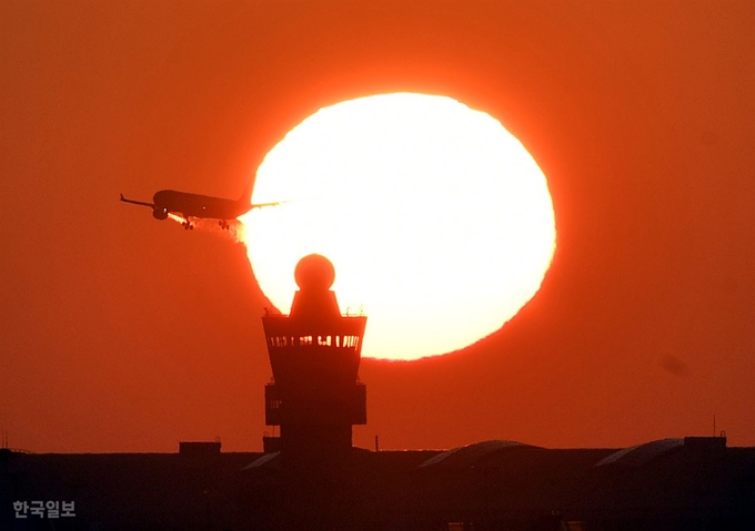 인천공항 제2여객터미널 관제탑 위로 떠오르는 해를 뚫고 비행기가 날아가고 있다.영종도=고영권 기자