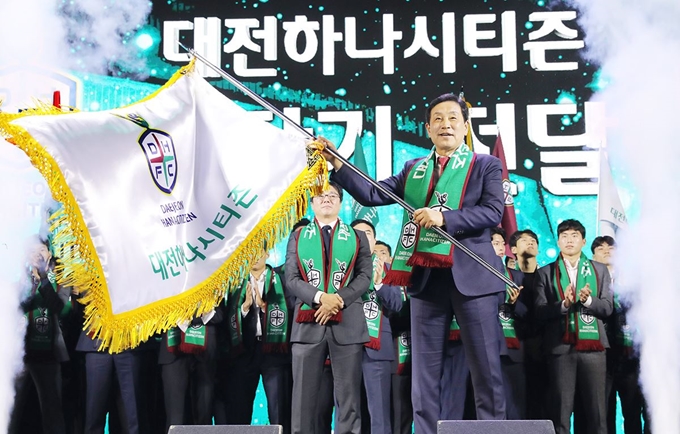 김정태 하나금융그룹 회장이 지난 4일 대전 충무실내체육관에서 열린 프로축구단 ‘대전하나시티즌’ 창단식에서 구단기를 흔들고 있다. 바로 뒷줄 가운데는 황선홍 대전하나시티즌 감독.하나금융그룹 제공