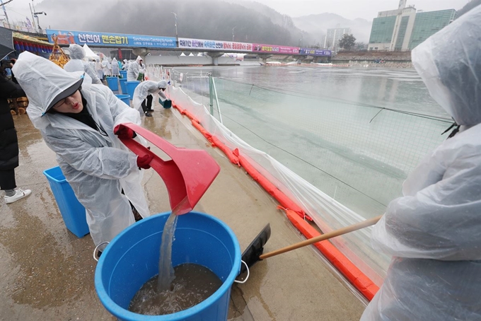 겨울비가 내린 7일 오전 강원 화천군 산천어축제장에서 공무원들이 얼음낚시터 행사장으로 흘러 들어가는 물을 퍼내고 있다. 화천=연합뉴스