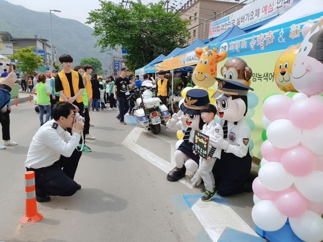 경찰관이 ‘함께해유 착한운전’캠페인에 참여한 어린이에게 사진을 찍어주고 있다. 이 캠페인은 경찰이 ‘엄마 아빠 함께해유 착한운전’ 피켓을 든 어린이를 즉석카메라로 촬영해 사진을 뽑아주면 어린이는 그 사진을 부모의 차량에 부착하는 방식으로 진행된다. 충북경찰청 제공