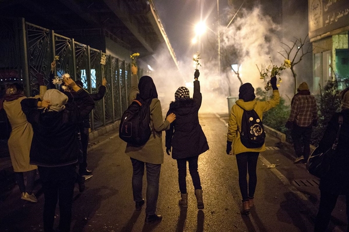 지난 11일 이란 수도 테헤란 시내에서 우크라이나 여객기 격추사건으로 숨진 희생자들을 기리기 위해 모인 시민들이 경찰의 최루가스 진압에 맞서 꽃을 흔들며 저항하고 있다. 테헤란=AP 연합뉴스