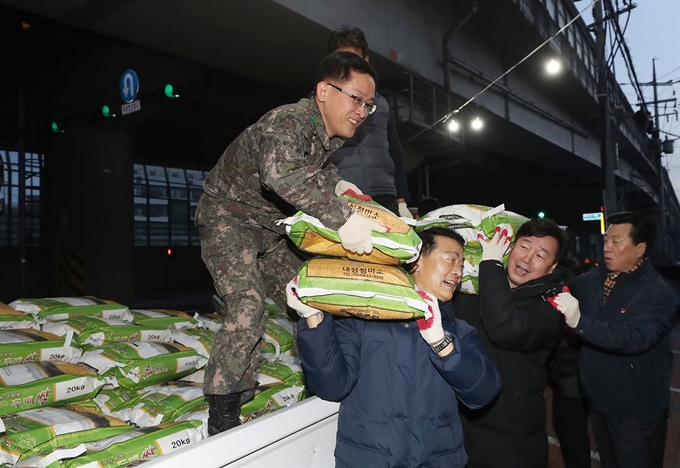 이승로 성북구청장(왼쪽)과 더불어민주당 기동민 의원이 16일 서울 성북구 월곡2동 주민센터에서 '얼굴없는 천사'로부터 배달된 쌀을 옮기고 있다. 월곡2동 주민센터는 2011년부터 10년째 이름을 알리지 않고 쌀을 기부해온 한 시민의 뜻을 기리기 위해 이날 10주년 기념행사를 실시했다. 연합뉴스