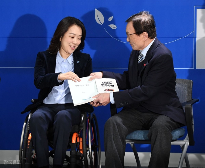 [저작권 한국일보] 이 대표가 최 교수에게 민주당 당헌.당규집과 당원 교과서를 전달하고 있다. 홍인기 기자