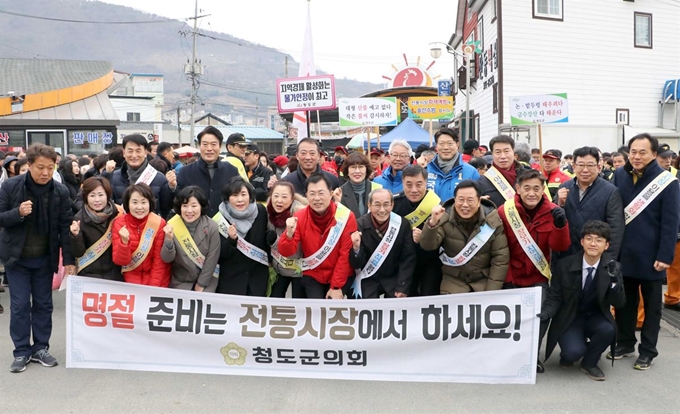 지난 19일 경북 청도군 고수리 청도장에서 박기호(앞줄 왼쪽 6번째) 청도군의회 의장, 이승률(7번째) 청도군수, 군의원들과 의회 직원들이 제수용품을 직접구매하고 상인 고충을 청취하는 등 현장 의정활동을 펼치고 파이팅을 외치고 있다. 청도군의회 제공