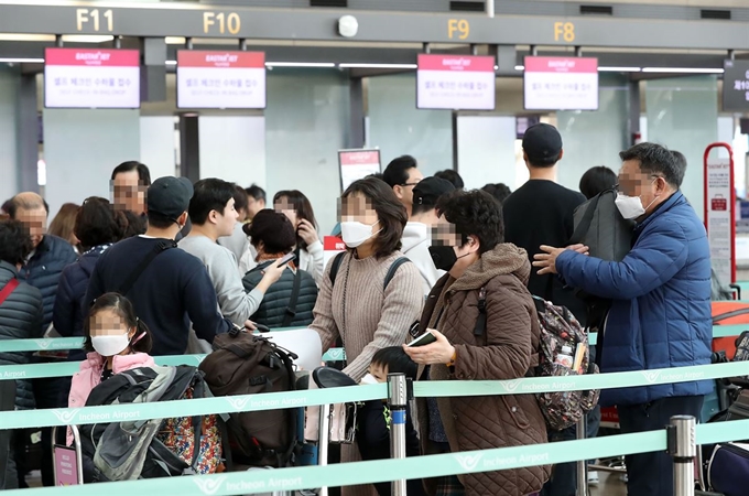 설 명절 연휴를 하루 앞둔 23일 신종 코로나바이러스로 인한 '우한 폐렴' 전염을 우려한 여행객들이 인천국제공항 제1여객터미널 출국장에서 마스크를 쓴 채 탑승수속을 하고 있다. 연합뉴스