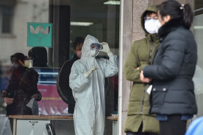 중국 우한의 한 병원에서 방호복을 입은 간호사가 체온계를 들여다보고 있다. 우한=AFP 연합뉴스