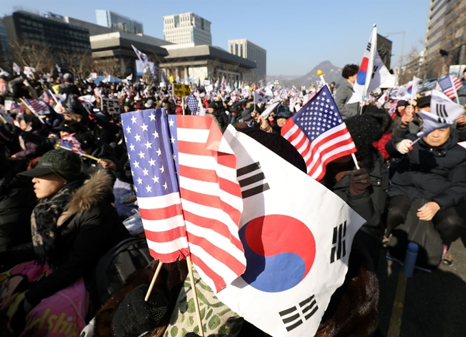 지난 18일 서울 종로구 교보빌딩 앞에서 문재인하야범국민투쟁본부 주최로 열린 '대한민국 바로세우기 국민대회'에서 참가자들이 태극기와 성조기를 흔들고 있다. 뉴시스