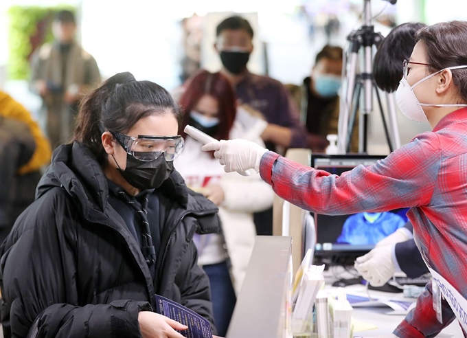 29일 중국 발 항공기로 인천국제공항에 도착한 승객이 마스크와 고글을 착용한 채 발열 검사를 받고 있다. 영종도=서재훈 기자