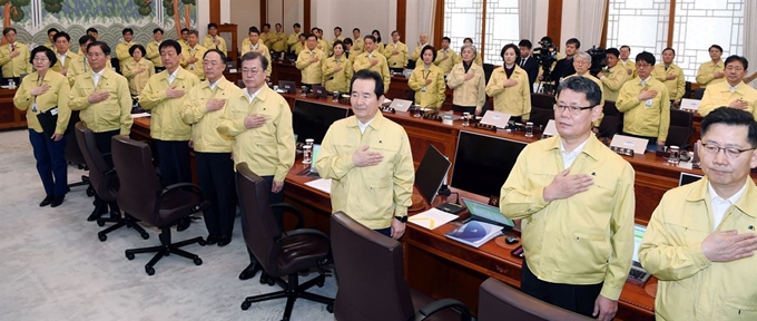 4일 청와대에서 열린 신종 코로나바이러스 대응 국무회의에서 문 대통령과 참석자들이 민방위 복장으로 국민의례를 하고 있다. 왕태석 선임기자