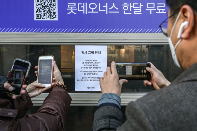 7일 오후 서울 중구 롯데백화점 본점 앞에서 시민들이 롯데백화점 정문에 붙은 휴점 안내문을 사진으로 찍고 있다.롯데백화점 본점이 신종 코로나바이러스 감염증 확진자 방문 여파로 이날 오후 2시부터 임시 휴점 후 전체 방역 작업에 들어갔다. 롯데백화점은 질병관리본부로부터 23번째 확진자가 지난 2일 본점에 방문했다고 이날 공식 통보받았다. 연합뉴스