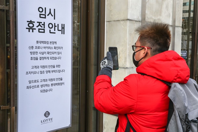 7일 오후 서울 중구 롯데백화점 본점 앞에서 시민들이 롯데백화점 정문에 붙은 휴점 안내문을 사진으로 찍고 있다.롯데백화점 본점이 신종 코로나바이러스 감염증 확진자 방문 여파로 이날 오후 2시부터 임시 휴점 후 전체 방역 작업에 들어갔다. 롯데백화점은 질병관리본부로부터 23번째 확진자가 지난 2일 본점에 방문했다고 이날 공식 통보받았다. 연합뉴스