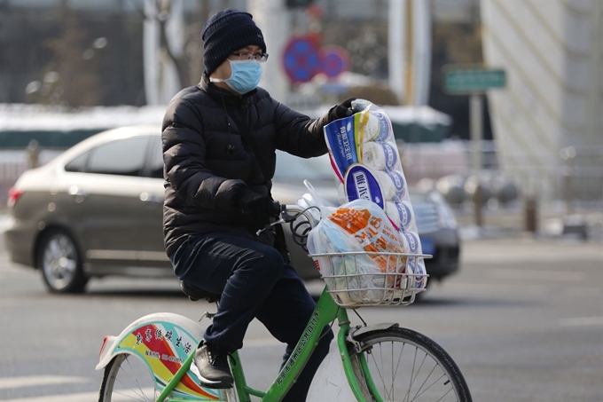 중국 베이징 시내에서 7일 마스크를 쓴 남성이 자전거에 생필품을 싣고 지나가고 있다. 베이징=EPA 연합뉴스