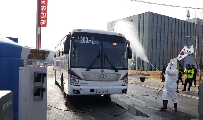 중국 후베이성 우한 교민을 수용 중인 충북 진천 국가공무원인재개발원 관계자가 7일 경비를 마친 경찰을 싣고 나오는 경찰버스를 소독하고 있다. 연합뉴스