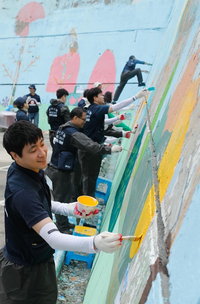 대림그룹 임직원들이 지난해 5월 서울 용산구 해오름빌에서 외부 벽화 작업을 하고 있다. 대림산업 제공