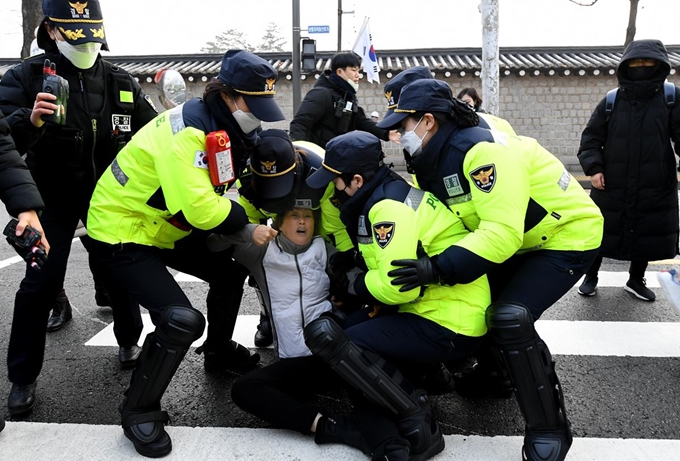 13일 오전 종로구청 관계자와 용역직원들이 서울 종로구 청와대 사랑채부터 정부서울청사 창성동 별관 인근까지 설치돼 있던 천막들을 철거하는 행정대집행을 벌이고 있는 가운데 항의하는 신도를 경찰이 끌어내고 있다. 왕태석 선임기자