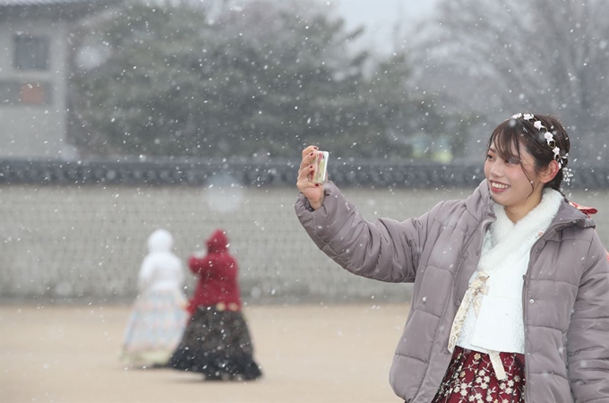 서울에 대설주의보가 내려진 16일 오전 한복을 입고 서울 종로구 경복궁을 찾은 외국인 관광객이 함박눈을 맞으며 기념촬영을 하고 있다. 연합뉴스