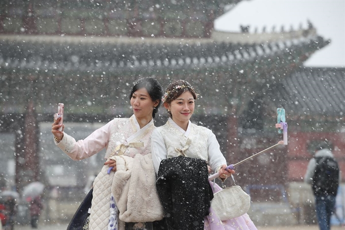 서울에 대설주의보가 내려진 16일 오전 한복을 입고 서울 종로구 경복궁을 찾은 외국인 관광객이 함박눈을 맞으며 기념촬영을 하고 있다. 연합뉴스