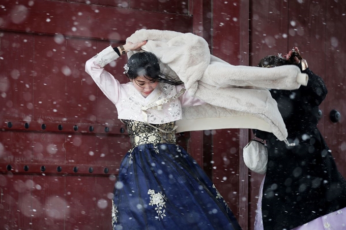 서울에 대설주의보가 내려진 16일 오전 한복을 입고 서울 종로구 경복궁을 찾은 외국인 관광객이 추위에 외투를 입고 있다. 연합뉴스