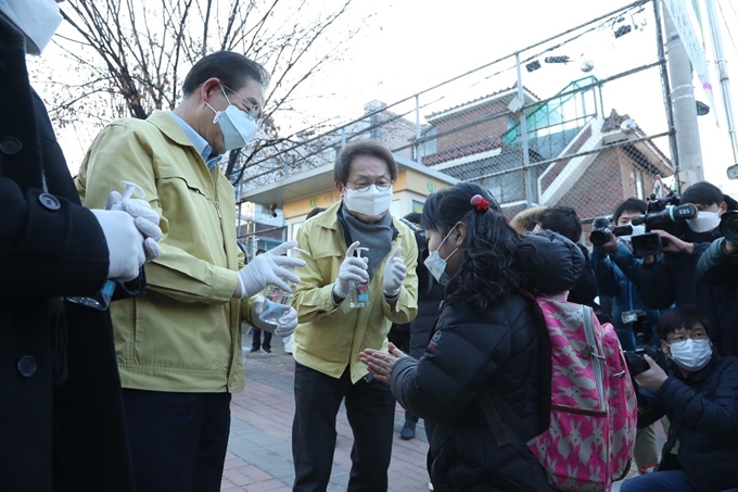 박원순 서울시장과 조희연(가운데) 서울시교육감이 지난 6일 서울 관악구 남부초등학교에서 등교하는 어린이들에게 손 소독제를 발라주고 있다. 연합뉴스