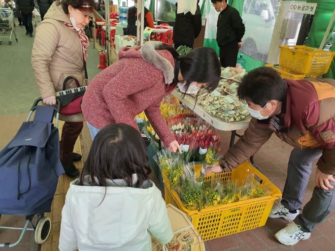 19일 경기 과천 경마공원 바로마켓에 개설된 ‘생거진천 농특산물 특별판매장’에서 시민들이 진천 특산물인 화훼류를 고르고 있다. 이 판매장은 마사회와 한국농수산식품유통공사가 우한 교민을 포용한 진천지역의 경제활성화를 지원하기 위해 마련했다. 충북도 노진호사무관 제공