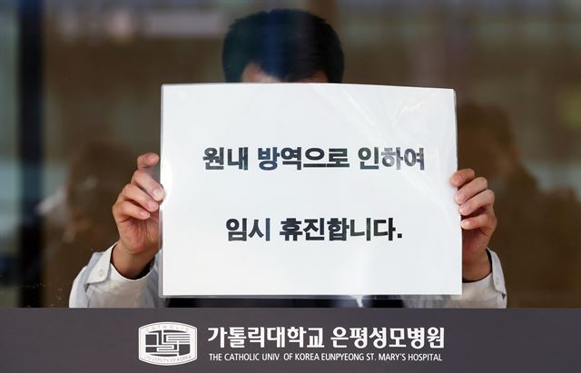 21일 오전 환자이송요원 중 1명이 신종코로나바이러스 감염증(코로나19) 1차 양성 판정을 받은 서울 은평성모병원에서 관계자가 휴진 안내문을 붙이고 있다. 연합뉴스