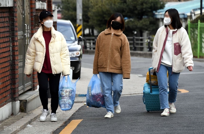 [저작권 한국일보]24일 오후 입국한 중국인 유학생(맨 오른쪽)이 서울 동대문구 이문동 주택가에 도착해 먼저 입국한 유학생 친구들과 함께 식료품점에서 장을 본 후 캐리어를 끌고 거주지로 향하고 있다. 중국에서 입국한 유학생들의 경우 14일간 격리생활을 해야 하는데 기숙사에서 도시락으로 끼니를 해결하는 학생들과 달리 외부 거주 학생들은 격리 기간 임의로 외출을 해도 이를 통제할 방법이 마땅치 않다. 고영권 기자