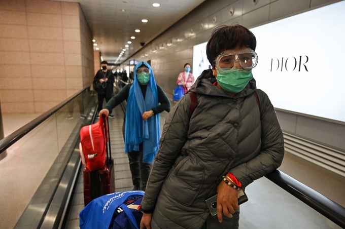 중국 상하이 푸동 공항에서 24일 마스크에 고글을 쓴 승객들이 무빙워크를 타고 이동하고 있다. AFP 연합뉴스