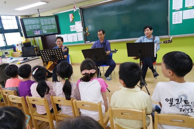 은퇴한 교장선생님들로 구성된 실버 밴드 '기타랑 하모랑' 멤버들이 정릉초등학교 돌봄교실에서 노래봉사를 하고 있다. 왼쪽부터 박길수, 권오선, 정구성씨. 박길수씨 제공