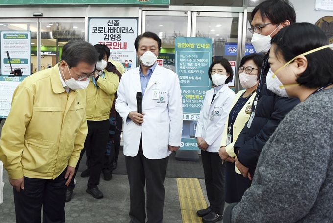 문재인 대통령이 25일 대구 서구 대구의료원에서 파견 의료진(오른쪽 사복 입은 두 명) 등 관계자에게 고개 숙여 감사를 표하고 있다. 대구=연합뉴스