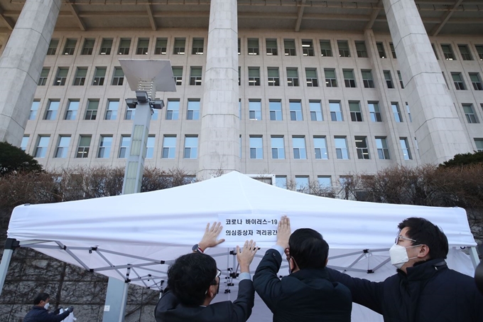 '코로나19' 여파로 일시 폐쇄됐던 국회가 방역작업을 마치고 다시 정상화된 26일 오전 국회 본관 민원실 입구 앞에서 관계자들이 코로나19 의심증상자 격리공간을 설치하고 있다. 연합뉴스