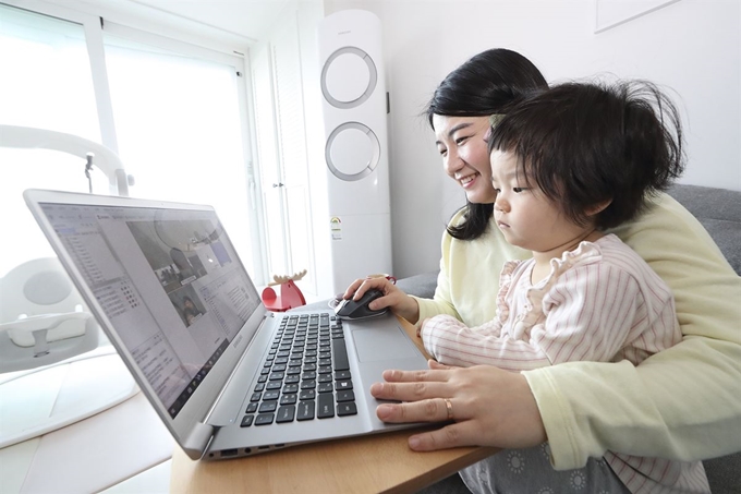 26일부터 재택근무를 시작한 KT 직원이 집에서 아이를 돌보며 화상회의 시스템을 활용해 업무를 보고 있다. KT 제공