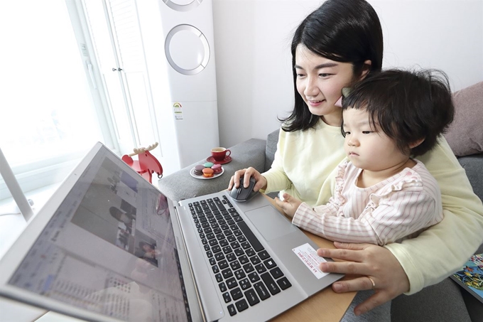 26일부터 재택근무를 시작한 KT 직원이 집에서 아이를 돌보며 화상회의 시스템을 활용해 업무를 보고 있다. KT 제공